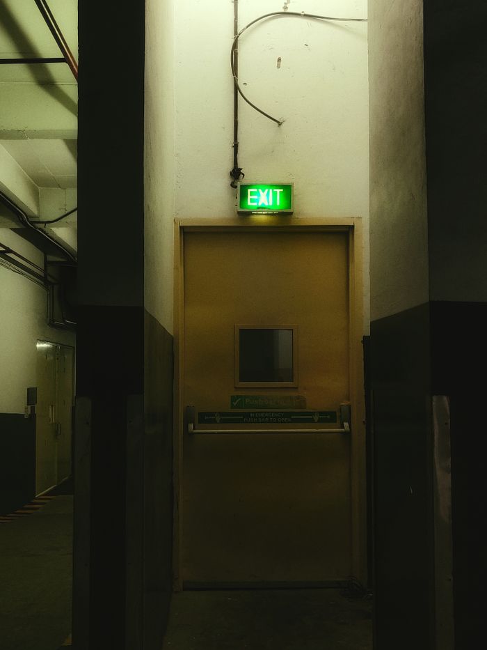 The Art of Drawing Readers In: Your attractive post title goes here Moody industrial interior featuring a well-lit emergency exit door.